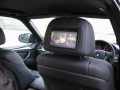 BMW X5. Two Screens trimmed into standard headrest. Single DVD player installed into rear of console. Cordless headphones.