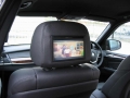 BMW X5. Two Screens trimmed into standard headrest. Single DVD player installed into rear of console. Cordless headphones.