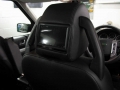 Land Rover Discovery 3. Two screens trimmed into standard headrest. Single DVD player installed into rear on centre console replacing cup holders. Cordless headphones